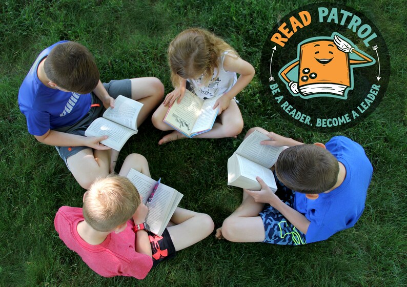 May include: Four children sit in a circle on green grass, each reading a book. A colorful logo in the background reads "Read Patrol: Be a reader. Become a leader."