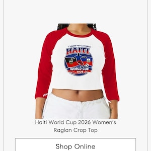 May include: A white and red raglan crop top with the text "HAITI WORLD CUP 2026" and a graphic of a soccer ball and a player. The shirt has three-quarter length sleeves.