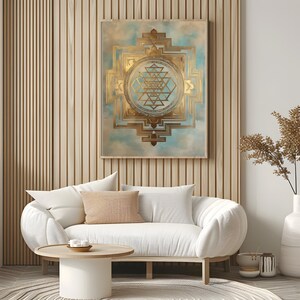 K&ouml;nnte beinhalten: Ein gold- und t&uuml;rkisgr&uuml;ner geometrischer Kunstdruck h&auml;ngt &uuml;ber einem wei&szlig;en Sofa mit einem hellbraunen Kissen. Das Kunstwerk zeigt ein detailliertes, symmetrisches Design mit einem zentralen kreisf&ouml;rmigen Element. Der Raum hat eine moderne, minimalistische &Auml;sthetik.