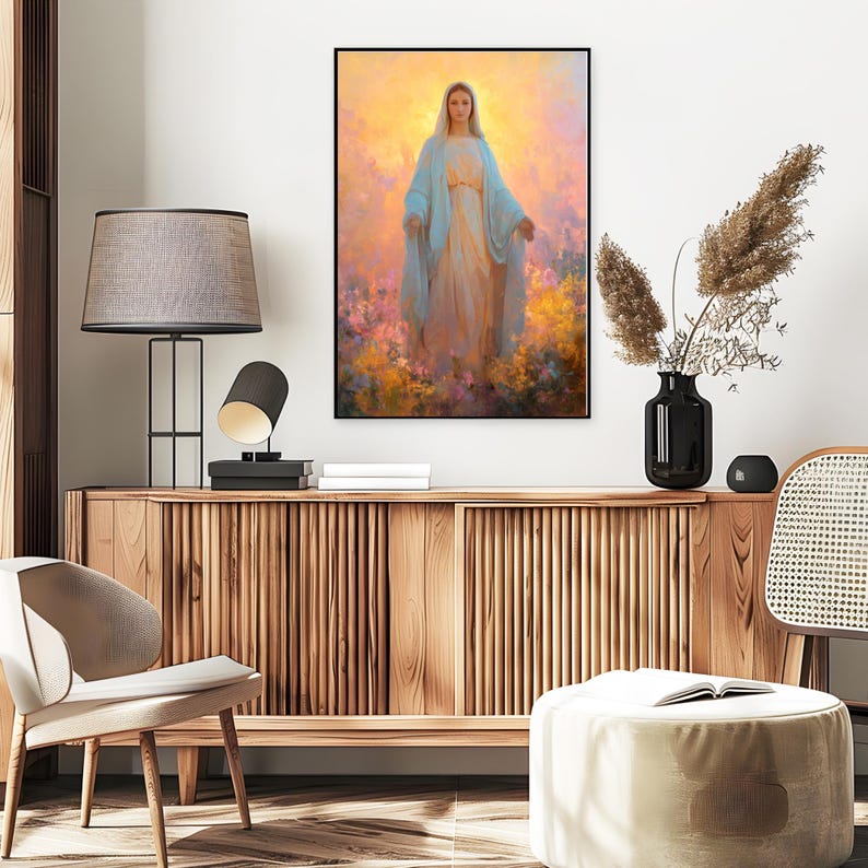 May include: A framed religious art print depicts a woman in a flowing blue robe and a white dress, surrounded by colorful flowers. The artwork has a soft, ethereal quality with a warm, golden background. The print is displayed above a wooden cabinet.