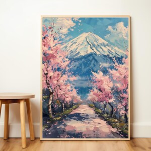 Pode incluir: Uma impress&atilde;o art&iacute;stica emoldurada retrata o Monte Fuji no Jap&atilde;o. A obra apresenta uma montanha coberta de neve, um caminho e cerejeiras em flor. A paleta de cores inclui tons de azul, rosa e branco.
