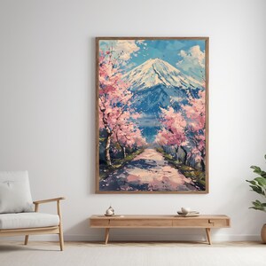 Pode incluir: Pintura emoldurada que retrata uma montanha coberta de neve sob um c&eacute;u azul. Cerejeiras em flor rosa ladeiam um caminho que leva &agrave; montanha. A obra de arte &eacute; exibida em uma parede branca, com uma moldura de madeira.