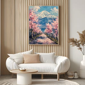 Pode incluir: Uma pintura de paisagem emoldurada retrata uma cena de montanha com um caminho ladeado por cerejeiras em flor. A obra de arte apresenta uma montanha com um pico coberto de neve, um c&eacute;u azul e flores rosa e brancas.