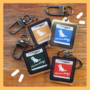 May include: Keychains featuring a dog graphic and the text "I Miss My Nintendogs" in various colors: orange, blue, green, and red. Each keychain has a silver-colored clasp.