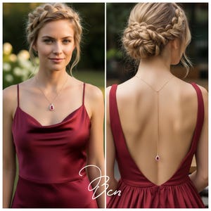 Puede incluir: Una mujer con un vestido de satén burdeos con espalda baja y tirantes finos. Lleva un collar de oro con una piedra preciosa roja en forma de lágrima. Su cabello está recogido en un moño. El vestido tiene un escote drapeado.