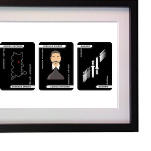 Può includere: Opera d'arte incorniciata con tre carte da gioco nere. Le carte mostrano illustrazioni e testo: "Orient Express", una mappa; "Hercule Poirot", un ritratto; e "Dagger", una collezione di coltelli. La cornice è nera.