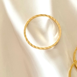 Puede incluir: Tres anillos de color dorado, dos de los cuales est&aacute;n apilados uno encima del otro. Los anillos son todos lisos y tienen un acabado brillante.