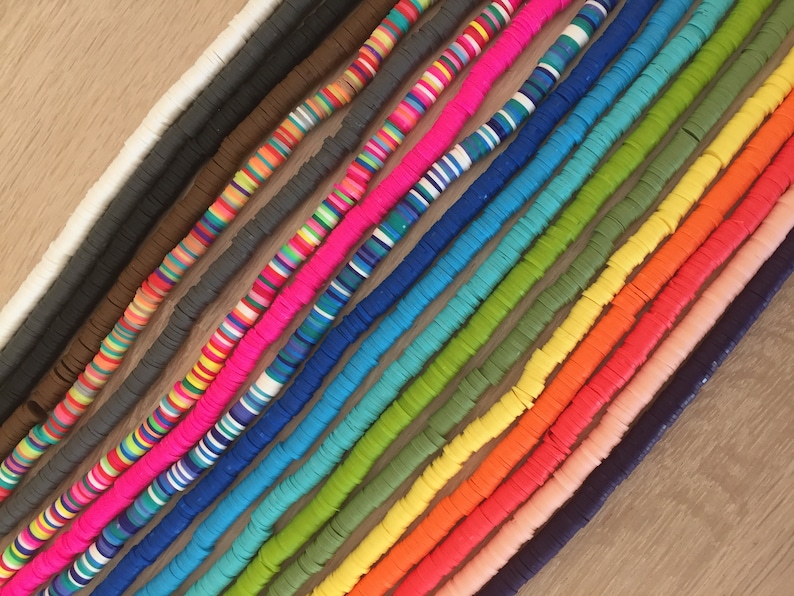 May include: A collection of colorful, round, flat, plastic beads. The beads are arranged in rows, with each row a different color. The colors include white, brown, gray, pink, blue, green, yellow, orange, and red.