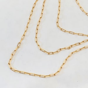 May include: A gold chain necklace with a delicate, linked design. The chain is made of small, rectangular links.
