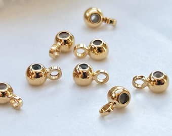 May include: Eight gold-toned metal bead caps with a small loop on one end. The bead caps are round and have a small hole in the center.