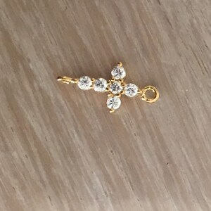 May include: A gold cross charm with clear cubic zirconia stones.