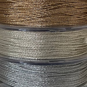 Peut inclure: Gros plan sur des bobines de fil métallique de différentes couleurs, notamment turquoise, rose, or, argent, gris et noir.