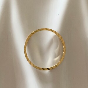 Puede incluir: Un anillo de banda de oro simple con un acabado texturizado y de corte de diamante.