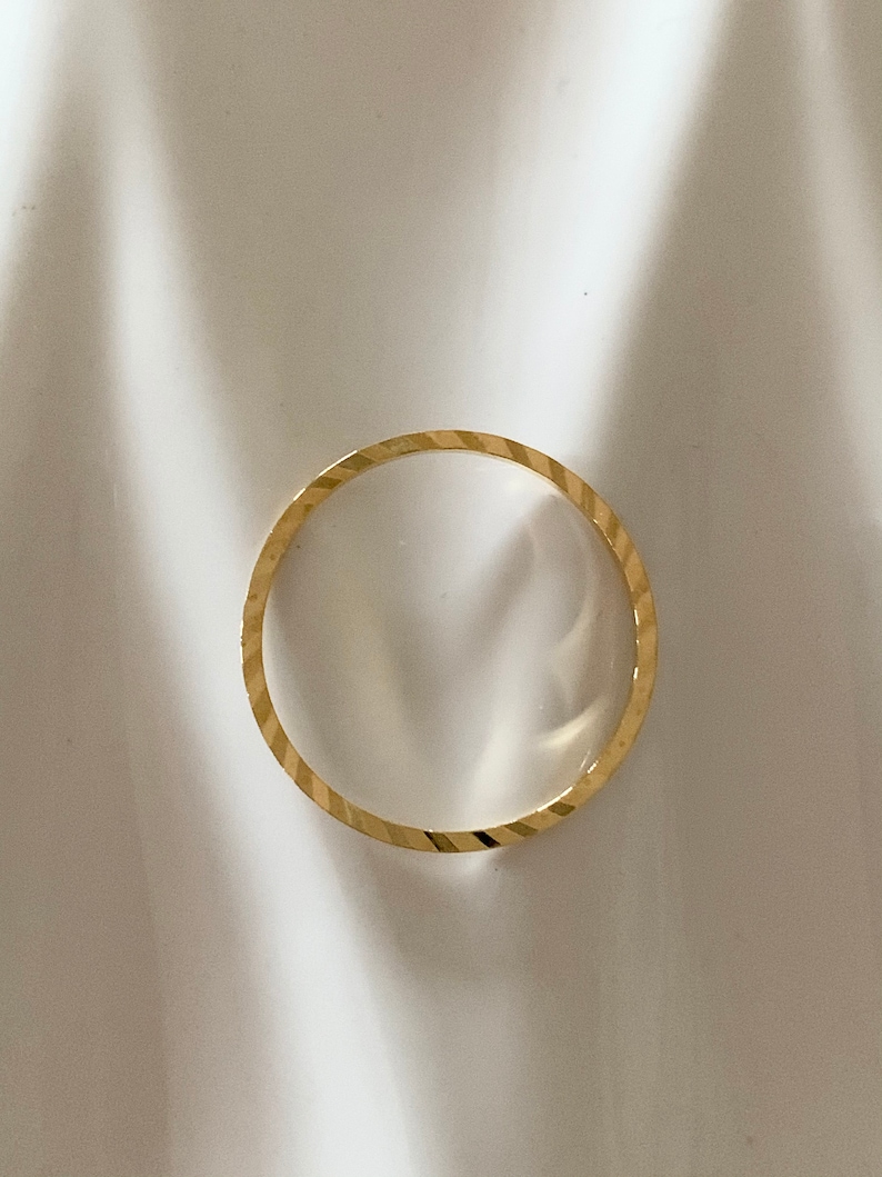 Puede incluir: Un anillo de banda de oro simple con un acabado texturizado y de corte de diamante.