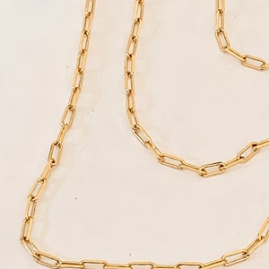 May include: A gold chain necklace with a simple, rectangular link design.