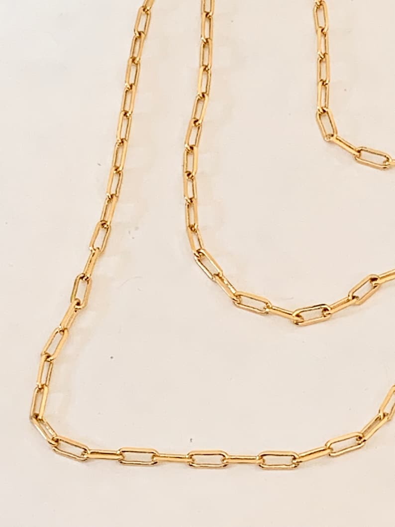 May include: A gold chain necklace with a simple, rectangular link design.