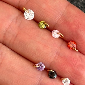 Op de afbeelding: Een set van zeven goudkleurige bedels met verschillende gekleurde strass steentjes. De bedels hebben een kleine lus om aan een armband of ketting te bevestigen.