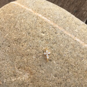 May include: A small gold cross charm with clear sparkling rhinestones.
