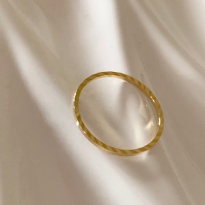 Puede incluir: Un fino anillo de banda de oro con un patr&oacute;n texturizado diagonal.