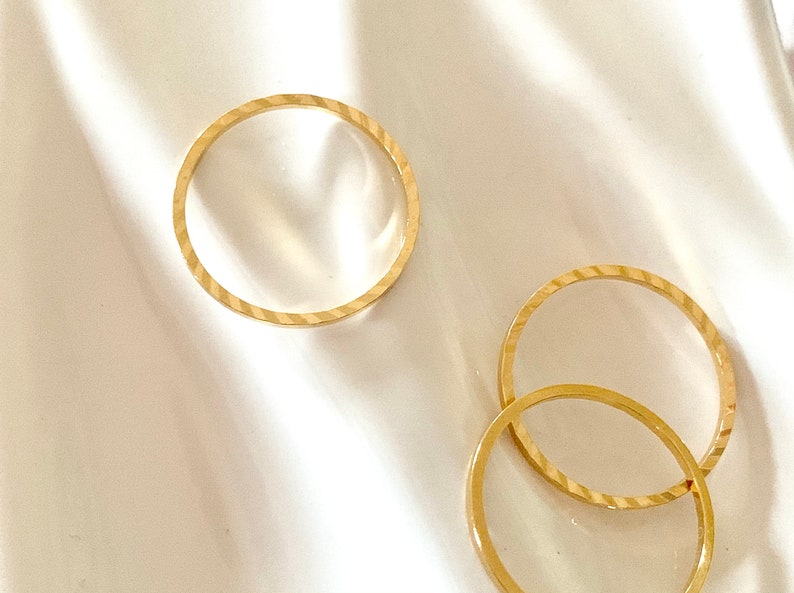 Puede incluir: Tres anillos de color dorado, dos de los cuales est&aacute;n apilados uno encima del otro. Los anillos son todos lisos y tienen un acabado brillante.