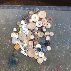 May include: A collection of assorted buttons in various colors, shapes, and sizes. The buttons are made of different materials, including plastic, metal, and wood. Some of the buttons have a decorative design, while others are plain.