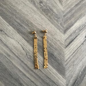 May include: A pair of gold dangle earrings with a chain link design.