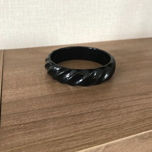May include: A black plastic bangle bracelet with a twisted design.
