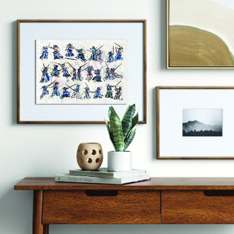 May include: Framed artwork showing a watercolour painting of stylized figures in action poses, possibly depicting a martial arts scene. The figures are dressed in blue, green, and red, with swords. The artwork is framed in a brown wooden frame.