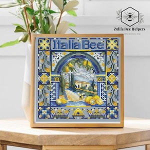 Puede incluir: Obra de arte de punto de cruz en un marco de madera. El diseño presenta un paisaje italiano con el texto "Italia Bee" en la parte superior. La paleta de colores incluye azules, amarillos y grises, con un motivo de abeja.