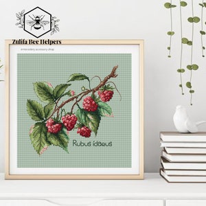 Puede incluir: Patrón de punto de cruz de una rama de frambuesas rojas con hojas verdes. El patrón se titula "Rubus Idaeus".