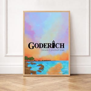 Puede incluir: Impresión artística enmarcada con el texto "Goderich Canada's prettiest town". La imagen muestra un paisaje costero con un faro, agua turquesa y un cielo en tonos naranja, azul y morado. La obra de arte está en un marco de madera.