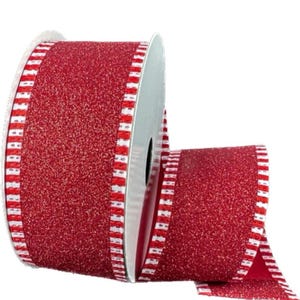 May include: A roll of red glitter ribbon with a white and red striped border. The ribbon is on a silver spool. The ribbon is likely used for gift wrapping, crafts, or holiday decorations.
