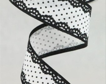May include: A roll of white ribbon with black polka dots and a scalloped lace edge. The ribbon is spiraling downwards, showcasing the pattern and texture. This decorative ribbon is suitable for crafts and gift wrapping.