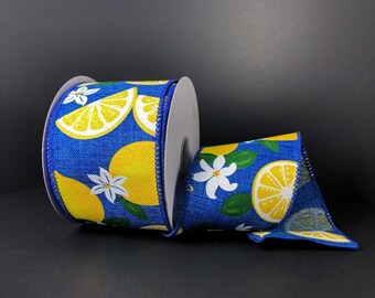 May include: A roll of decorative ribbon featuring a bright blue background with a lemon and floral pattern. The ribbon has a white edge and a repeating design of yellow lemons and white flowers. The ribbon is perfect for crafts and decorations.