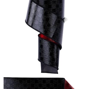May include: A spool of black ribbon with a subtle checkered pattern and a metallic red underside. The top label reads GLIMMER RIBBON. The ribbon has a shiny, reflective texture and is wound around a central core, showing both sides of the fabric.