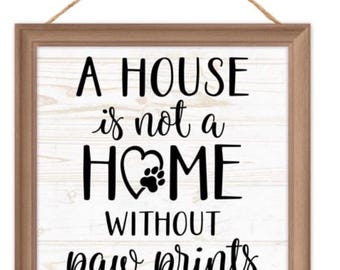 May include: A wooden framed sign with a white background and black text that reads "A house is not a home without paw prints". The sign has a heart with a paw print inside.