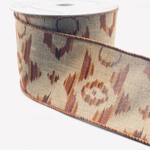 May include: A spool of decorative ribbon with a beige background and a repeating pattern in shades of brown and orange. The ribbon has a textured appearance and a brown border. Ideal for crafting and gift wrapping.