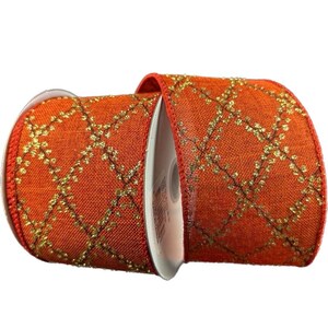 May include: A spool of orange ribbon featuring a woven texture and a repeating gold glitter diamond pattern across the surface. The edges of the ribbon are finished with a solid orange border, and the spool core is white plastic.