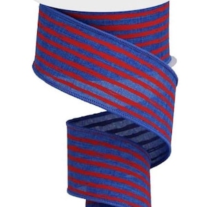 May include: A spool of blue ribbon with red horizontal stripes. The ribbon is made of a textured fabric and is partially unrolled, revealing the pattern. The spool has a white center.