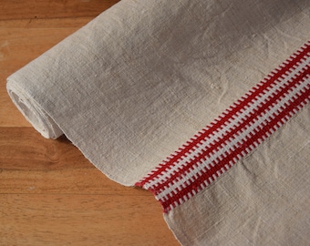 May include: A rolled up linen table runner with a red and white woven border.