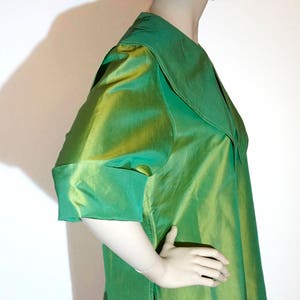 May include: A green silk blouse with a large, wide collar. The blouse has a slightly loose fit and is made of a shiny, iridescent fabric.
