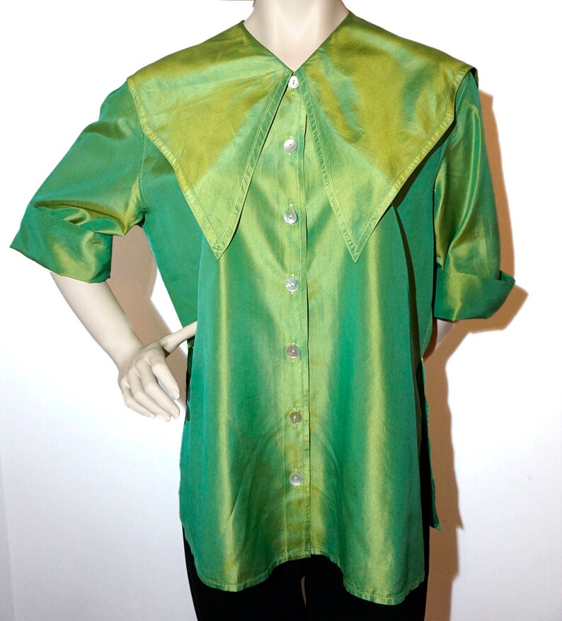 May include: A green and yellow silk blouse with a large, pointed collar and button fastening.