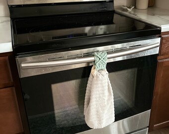 May include: Stainless steel oven with a black glass top and a white towel hanging from the handle. The oven has a digital display showing the time 6:26.