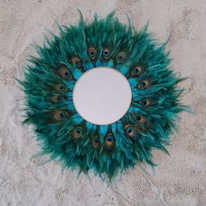 Peut inclure: Un miroir rond avec un motif de plumes de paon. Le miroir est entouré de plumes bleu turquoise avec des yeux bruns et bleus.