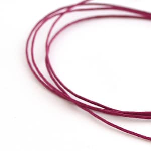 Peut inclure: Un gros plan d'une bobine de cordon ciré rose foncé. Le cordon est enroulé en cercle et est prêt pour des projets d'artisanat.