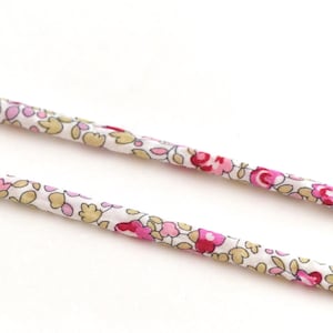 Könnte beinhalten: Zwei weiße Stoffkordeln mit einem rosa-braunen Blumenmuster.