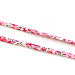 Può includere: Due pezzi di nastro bianco con un motivo floreale rosa e verde.