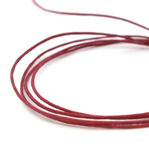 Peut inclure: Un gros plan d'une bobine de cordon de coton ciré rouge. Le cordon est enroulé serré et prêt à être utilisé pour des projets d'artisanat.