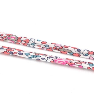 Peut inclure: Deux rubans en tissu blanc avec un motif floral rose et bleu.