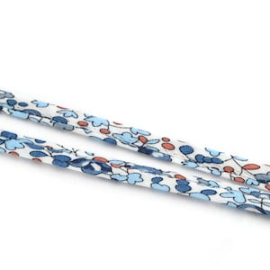 Puede incluir: Primer plano de dos correas de tela con un estampado floral. Las correas son blancas con diseños florales azules y naranjas. Las correas están en ángulo diagonal sobre un fondo blanco.
